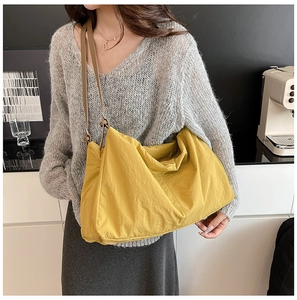 Spacious yellow nylon tote bag styled with a grey sweater for a casual daily look