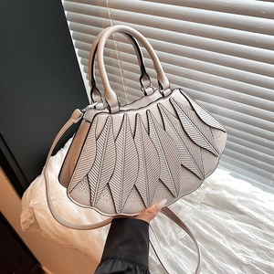 Detail der cremeweißen Handtasche mit Blatt-Design und feinen lasergeschnittenen Texturen