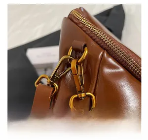 Detalle macro de los herrajes metálicos dorados y el cuero marrón de este bolso