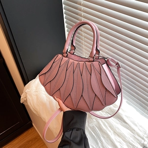 Detail einer hellrosa Handtasche mit Blatt-Design und eleganten schwarzen Ziernähten