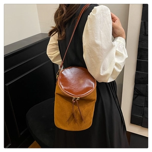 Detalle de bolso cubo bicolor en gamuza y cuero liso con tiradores de cremallera largos