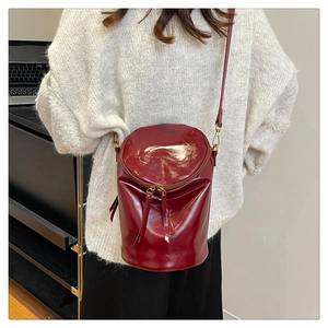 Detalle de bolso tipo cubo en charol burdeos con acabado brillante y herrajes dorados