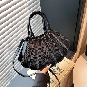 Detail der schwarzen Handtasche mit weißer Stickerei und dekorativen Lochmustern