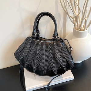 Detailansicht der schwarzen muschelförmigen Handtasche mit weißer Adertextur auf Büchern