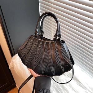 Detail einer schwarzen Handtasche mit weißem Federdekor, Doppelgriffen und Trageriemen