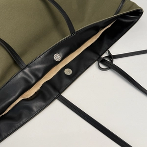 Dettaglio della borsa tote in tela verde militare con finiture in pelle e chiusura magnetica