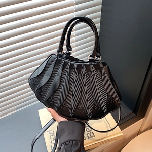 Detailansicht der schwarzen Abendtasche mit Blatt-Design und weißen Kontrastnähten