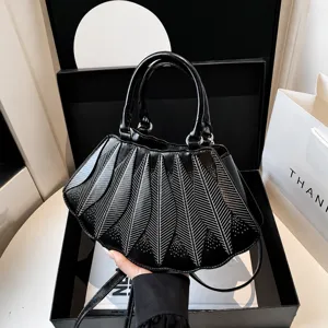Detail of black faux leather handbag with unique fan-shaped pleated design in gift box