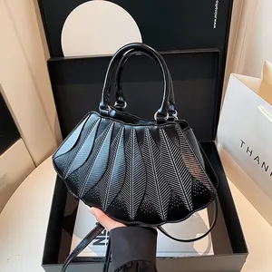 Detail einer schwarzen Handtasche aus Kunstleder mit fächerförmigen Falten in Geschenkbox