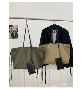 Dettaglio delle borse tote in tela verde militare e kaki con manici in pelle e pochette