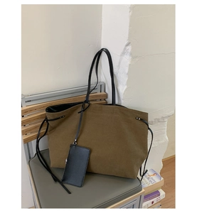 Vista dettagliata della borsa tote in tela oliva con coulisse laterale su una sedia