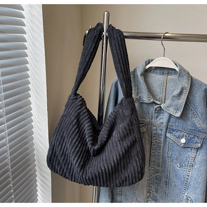 Detail of black corduroy tote bag showing soft ribbed texture and wide shoulder strap