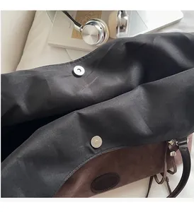 Detailansicht des silbernen Magnetverschlusses und Innenfutters der braunen Wildledertasche