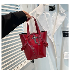 Close-up of red leather bucket bag featuring silver cross charms and metal rivet details