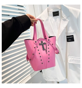 Detail of bright pink bucket bag featuring gothic black cross and silver metal studs