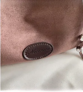 Detail der altrosa Wildledertasche mit Leder-Markenpatch und silbernen Kordelzug-Perlen