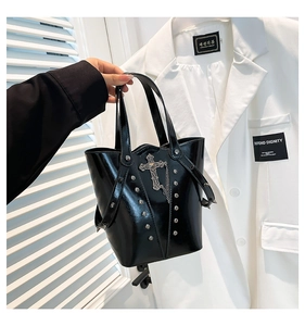 Close-up of black punk bucket bag with silver rivets and vintage cross pendant detail