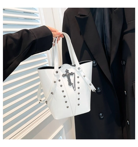 Detail of white bucket bag with punk silver metal studs and a small cross charm pendant
