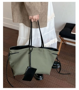 Detail of army green canvas tote bag with black leather handles and matching pouch