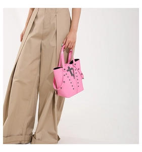 Detail of pink punk bucket bag with black metal rivets and cross charm decoration