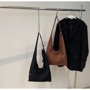 Detail view of large suede tote bags in black and brown hanging in a fashion showroom