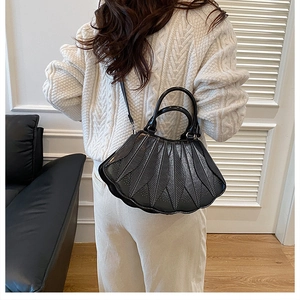 Detail der schwarzen Handtasche mit gefächertem Lagen-Design und Wellenkanten