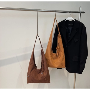 Detail of hobo bags with knotted shoulder straps and metal rings in suede texture