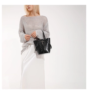Detail view of glossy black punk bucket bag with silver studs and a cross pendant