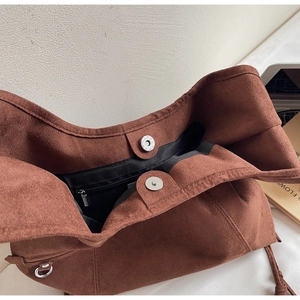 Detailed interior of brown suede tote bag featuring magnetic buckles and a zipper pocket