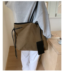 Detail of tan canvas tote bag with black leather straps and detachable pouch on side