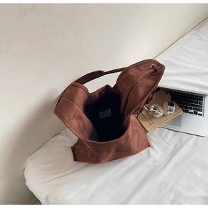 Detail of a brown suede tote bag featuring a spacious interior with laptops and books