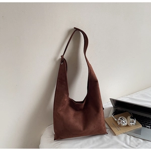 Detail of minimalist dark brown suede tote bag styled with laptop and headphones