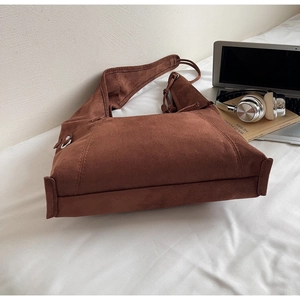 Detailed view of brown faux suede tote bag with knotted shoulder strap and side stitching