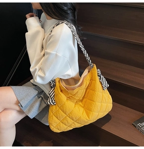 Detail of yellow quilted tote bag featuring diamond stitching and striped woven strap