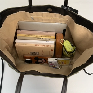 Vista interna della grande borsa tote in tela verde con spazio per laptop e vari libri