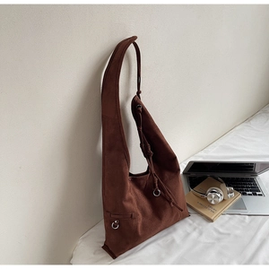 Detail of dark brown suede tote bag with drawstring knot and silver metal ring hardware