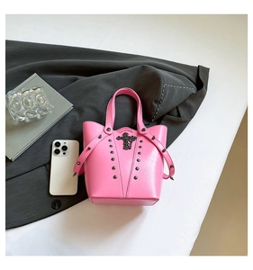 Detail of hot pink bucket bag with silver cross relief, rivets and shoulder strap