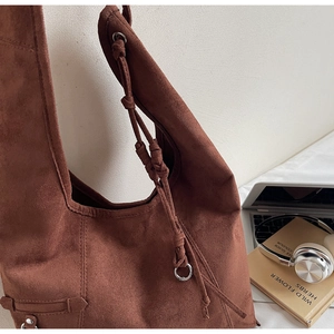 Detail of suede shoulder bag featuring a decorative knot and metallic silver rings