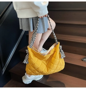 Quilted yellow tote bag detail with diagonal striped strap and side bow decoration