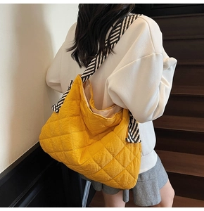 Detail of quilted bright yellow tote bag with black and white striped shoulder strap