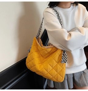 Close-up of yellow quilted tote bag featuring a striped braided strap with knot detail