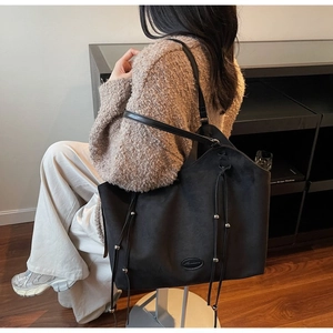 Detailansicht der schwarzen Wildledertasche mit dekorativem Kordelzug und Silberperlen