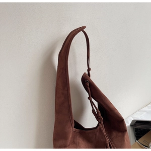 Detail of brown suede tote bag with woven drawstring decoration and soft texture