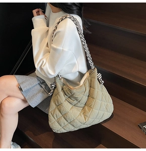 Close-up of olive green quilted tote bag with a stylish black and white striped strap