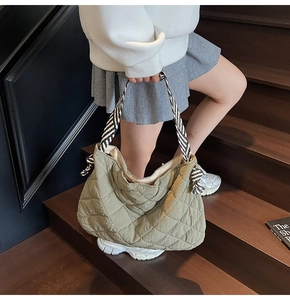 Olive green quilted tote bag with black and white woven handles on a model