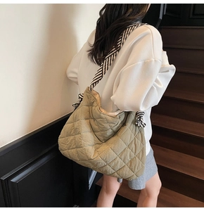 Olive green quilted tote bag with black and white striped strap shown on person