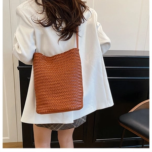 Detail of hand-woven brown tote bag showing tight cross-knit texture and slim leather strap