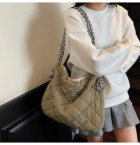 Olive green quilted tote bag with black and white striped shoulder strap and knot detail