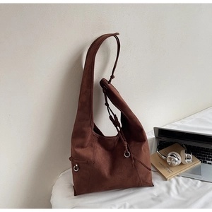 Detail of dark brown suede tote bag featuring silver ring and drawstring accents