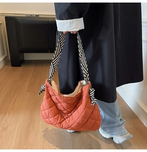 Detail of burnt orange quilted tote bag with striped woven strap and knot decoration